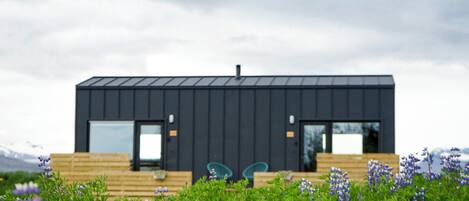 A modern, dark-colored building with large windows and a wooden deck.