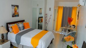 Et hotelværelse med en seng, et natbord, et skrivebord, en stol og et spisebord med stole.
