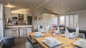 A modern kitchen with white cabinets, a wooden countertop, and a built-in microwave. - Lakeside 20 (Carnforth)