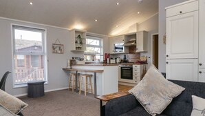 A compact living space with a kitchenette, a sofa, and a dining area. - Lakeside 20 (Carnforth)