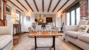 Un salon chaleureux avec une table en bois, un canapé à rayures et un mur en briques.
