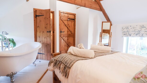 Une chambre à coucher avec un grand lit, un plafond en bois, une baignoire et une porte au design inspiré des portes de grange.