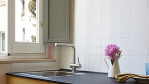 A kitchen with a sink, a window, and a vase with flowers. - Trastevere Home - Santa Maria with beautiful view on the square (Roma)