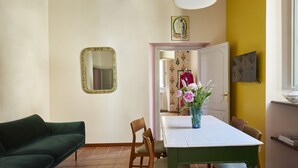 A dining area with a table, chairs, a vase with flowers, a mirror, and a door leading to another room. - Trastevere Home - Santa Maria with beautiful view on the square (Roma)