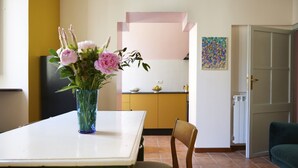 A dining area with a table, chairs, and a vase of flowers. - Trastevere Home - Santa Maria with beautiful view on the square (Roma)