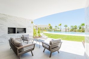 A modern outdoor living area with a pool, lounge chairs, and a kitchen area with a built-in grill. - Lakes 24 at Praia da Falesia Vilamoura (Loulé)