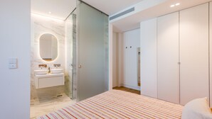 Una camera da letto moderna con un letto grande, un bagno dotato di cabina doccia in vetro e un armadio a muro.