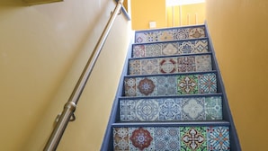A staircase with a metal handrail and a series of colorful, patterned tiles on the steps.