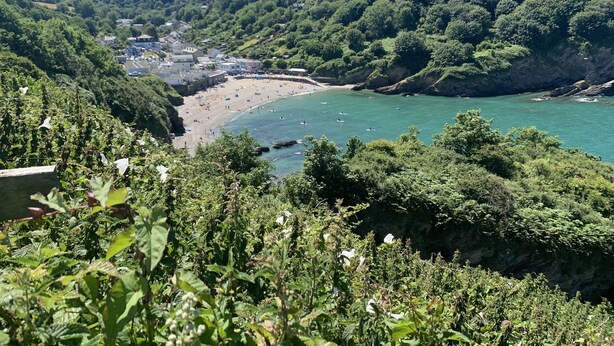 A coastal landscape with a beach, cliffs, and a town in the background.