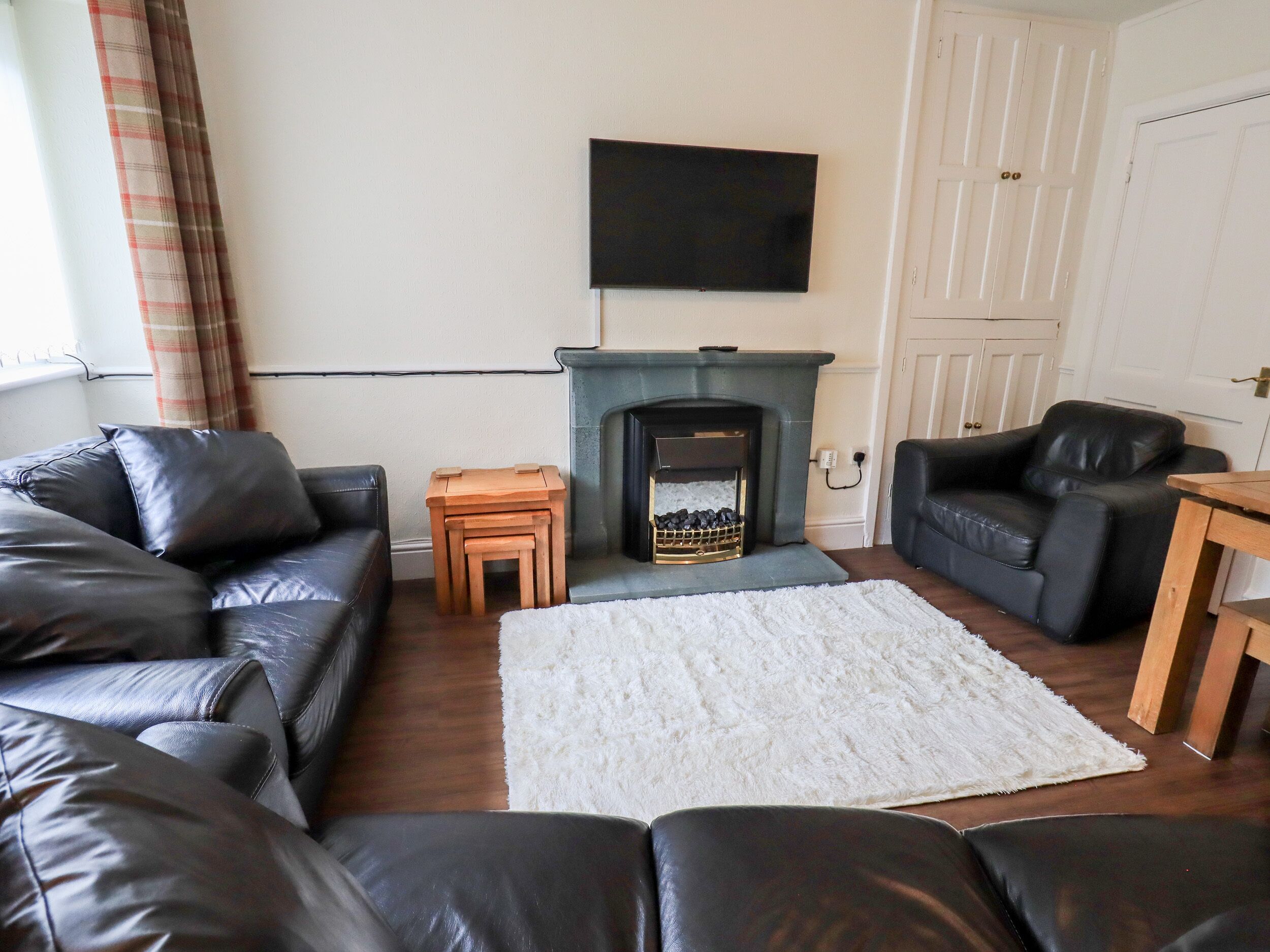 A living room with a fireplace, a television mounted above it, and two leather sofas.