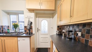 A kitchen with wooden cabinets, a dishwasher, a toaster, and a coffee maker. - 6 Calgarth View (Windermere)
