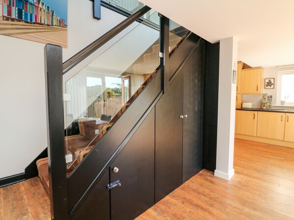A modern staircase with a glass railing, wooden steps, and a dark finish.