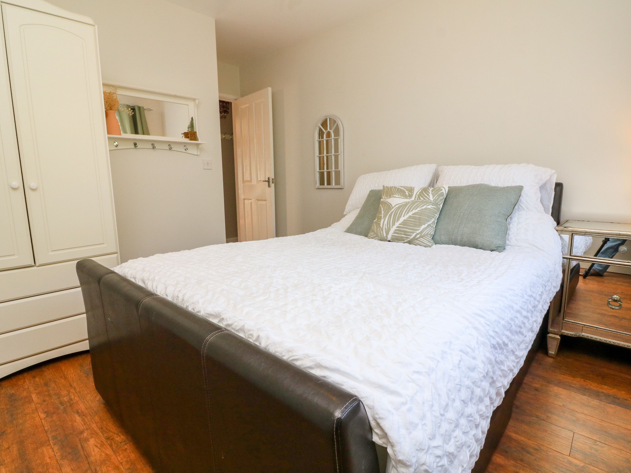 Un dormitorio con cama, armario y mesita de noche.