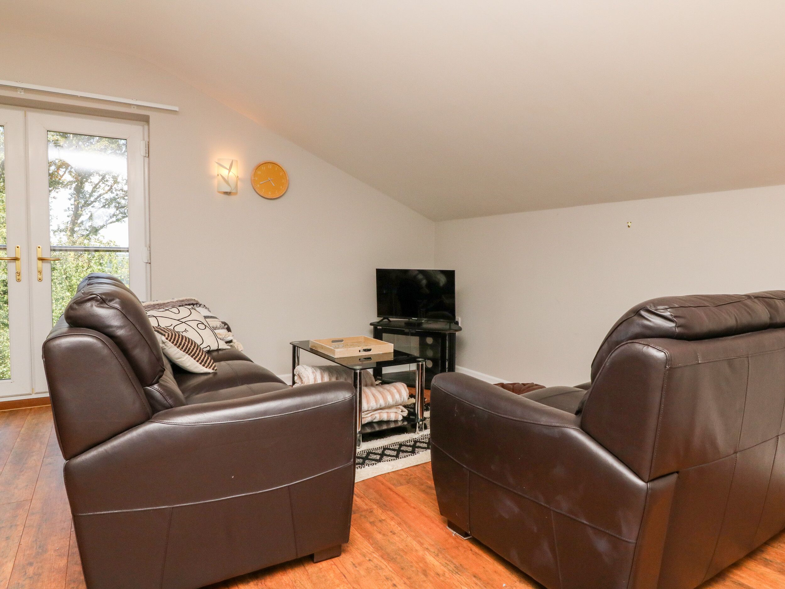 A living room with two leather sofas, a television, and a small table.