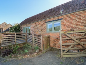 A brick building with a wooden gate, a window, and a brick wall. - Shire Cottage (Driffield)
