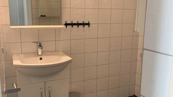 Un baño con lavamanos blanco, espejo y retrete.