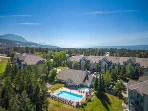 A resort with multiple buildings, a swimming pool, and a mountainous backdrop.