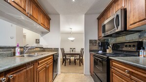 A kitchen with wooden cabinets, a stainless steel microwave, and a stove. - Alpine Retreat | Pool | Hot Tub | Affordable (Radium Hot Springs)