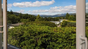Vista de uma varanda com vista para uma paisagem verde exuberante e montanhas ao longe.