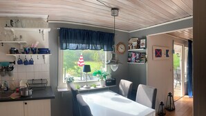 Eine Küche mit Esstisch, Stühlen und einem Fenster mit Blick auf einen Garten.