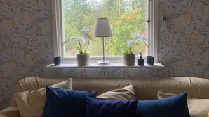 Ein Zimmer mit Fenster, einer Couch und zwei Blumentöpfen auf der Fensterbank.