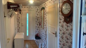 Ein Korridor mit floralem Wandpapier, einer Holzbalkendecke, einer Wanduhr und einer Bank.