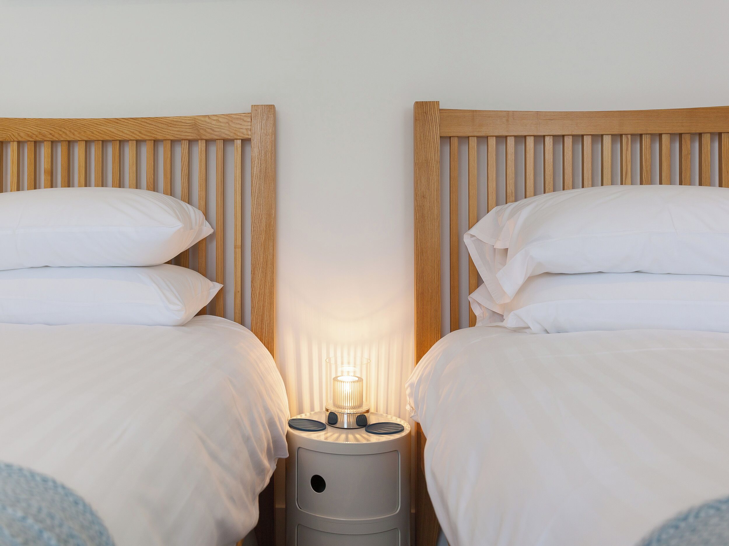 Une chambre double avec deux lits, chacun doté d’une tête de lit en bois et de linge de lit blanc.