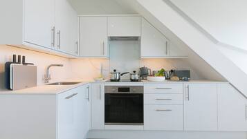 A modern kitchen with white cabinetry, a built-in oven, and a sink.