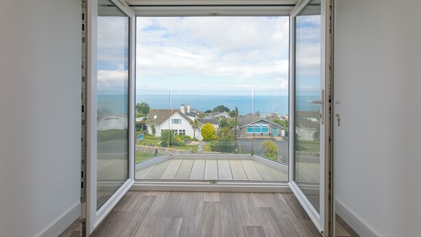 Uma varanda com vista para casas e o mar.