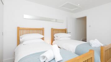 Een hotelkamer met twee houten bedden, wit beddengoed en een spiegel boven de bedden.