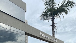 Un bâtiment moderne doté d’une grande façade en verre et d’une enseigne indiquant « Palmeira Dourada ».