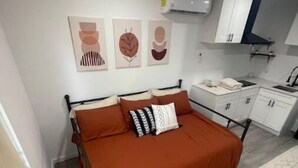 Une chambre avec un lit, un bureau et un coin cuisine.