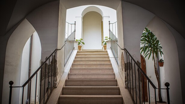 A staircase with a handrail, flanked by white walls and arches, leading to a higher floor. - Passetto De Lectis in Ortona (Ortona)