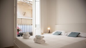 A bedroom with a bed, pillows, a nightstand, a lamp, and a window with a view of a balcony. - Passetto De Lectis in Ortona (Ortona)