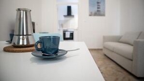A modern living room with a white sofa, a coffee table with a blue cup and saucer, and a silver coffee maker. - Passetto De Lectis in Ortona (Ortona)