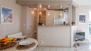A modern kitchen with white cabinets, pendant lights, and a dining area with a table set for two. - Le Belvédère by Interhome (Cabourg)