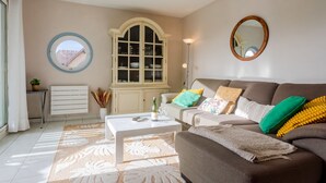 A living room with a sofa, a coffee table, a cabinet, and a window with curtains. - Le Belvédère by Interhome (Cabourg)