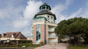 A building with a tower, a gated entrance, and a clear sky. - Le Belvédère by Interhome (Cabourg)