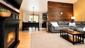 Una sala de estar con chimenea, sofá, televisor y un panel decorativo de madera.