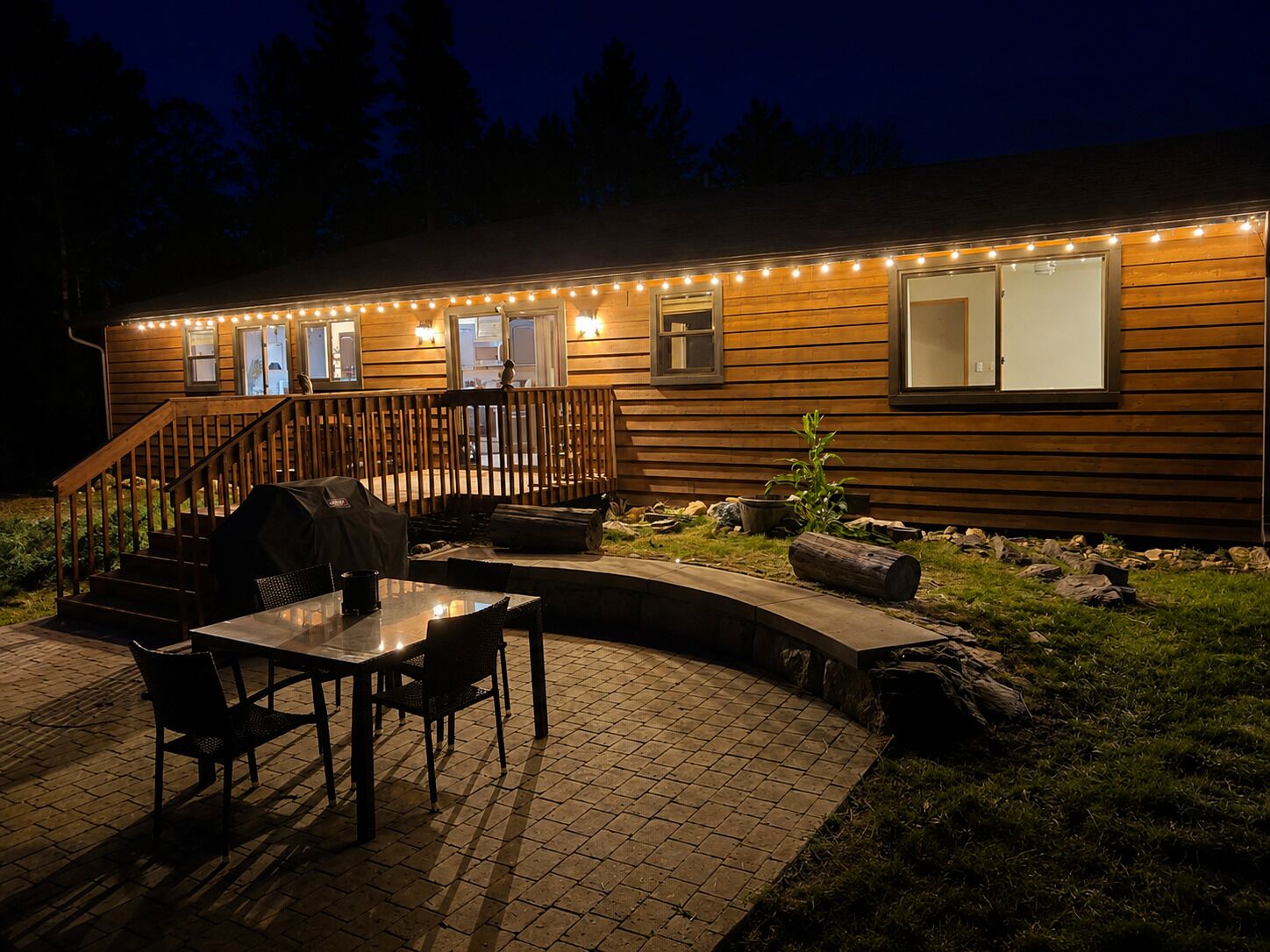 Eine Holzhütte mit überdachter Terrasse, Sitzgelegenheiten im Freien und Lichterketten.