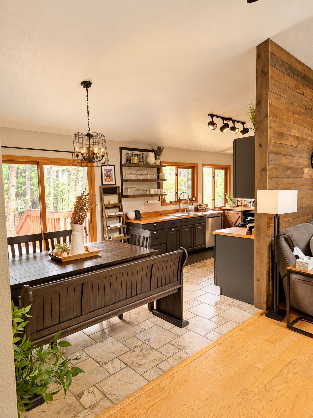 A modern kitchen with a wooden dining table, a bench, and a chandelier.