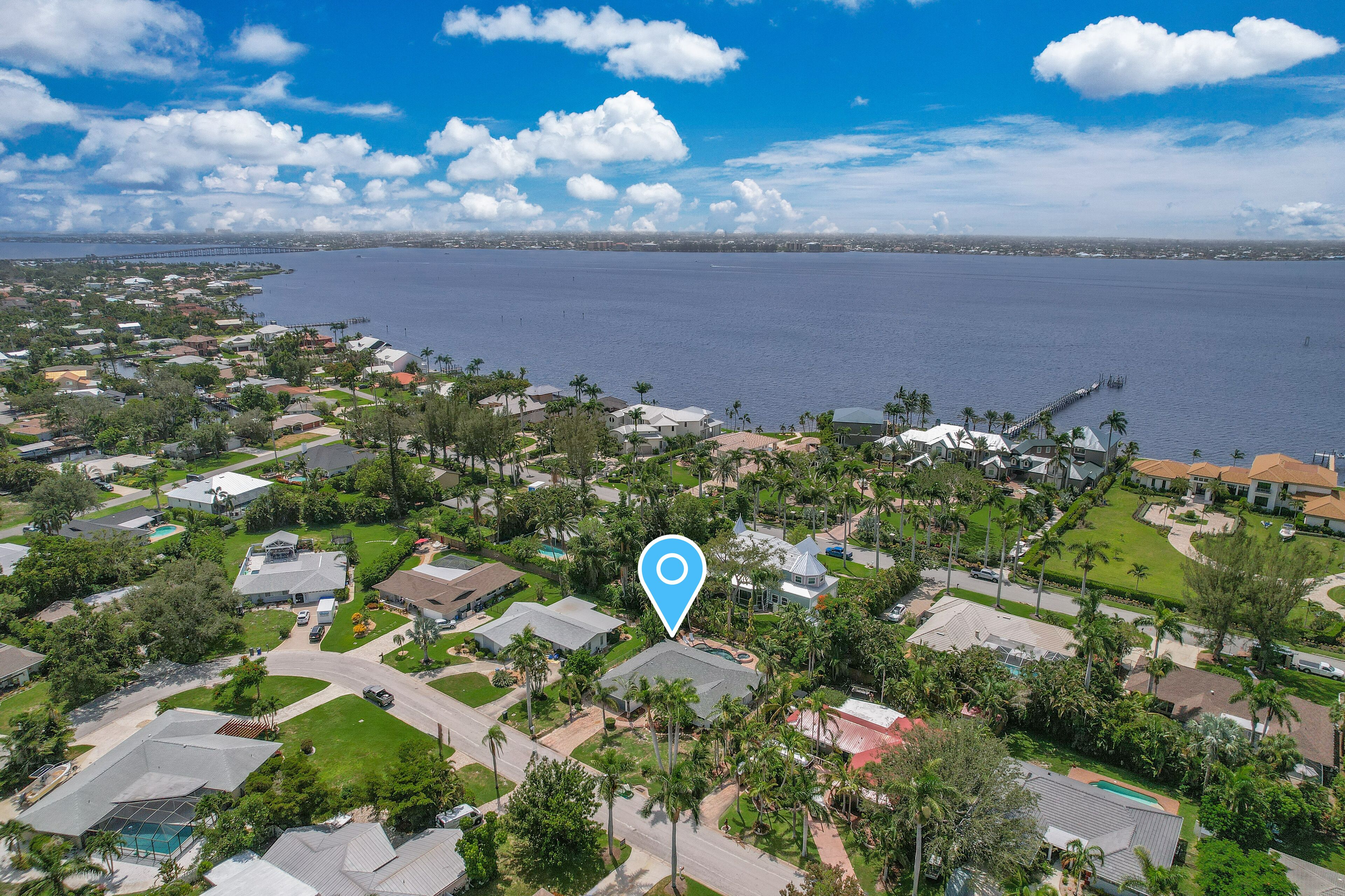 Luchtbeeld van een woongebied met huizen, palmbomen en een waterpartij op de achtergrond.
