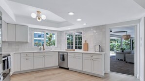A spacious kitchen with white cabinetry, a dishwasher, and a large window offering a view of the outdoors.