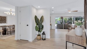 A spacious living area with a dining table, a large potted plant, and a ceiling fan.