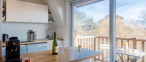 Une cuisine moderne avec un plan de travail en bois, une machine à café, une bouteille de vin et une tasse.