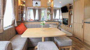 Un interior de autocaravana acogedor, con comedor, asientos, cocina y televisor.