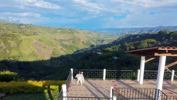 A terrace with a view of a valley, a person sitting, and a pergola structure.