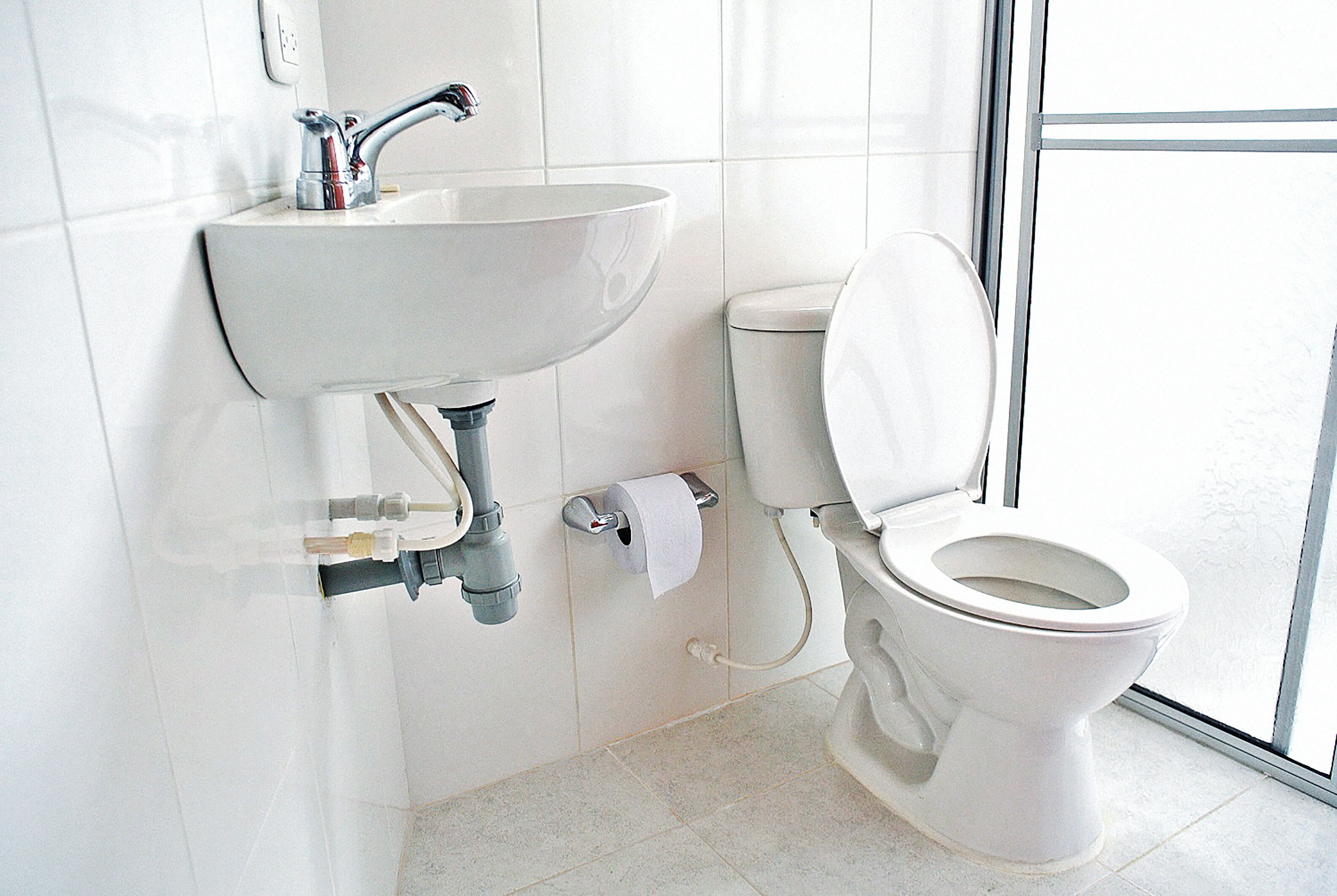 A bathroom with a white sink, toilet, and a window providing natural light.