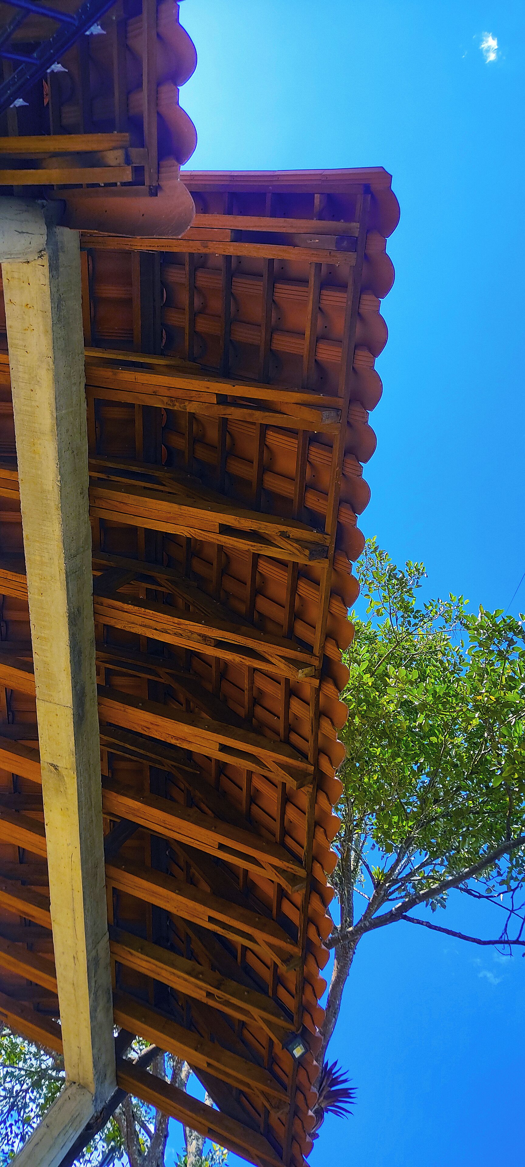 A wooden structure with a tiled roof and a clear blue sky in the background.