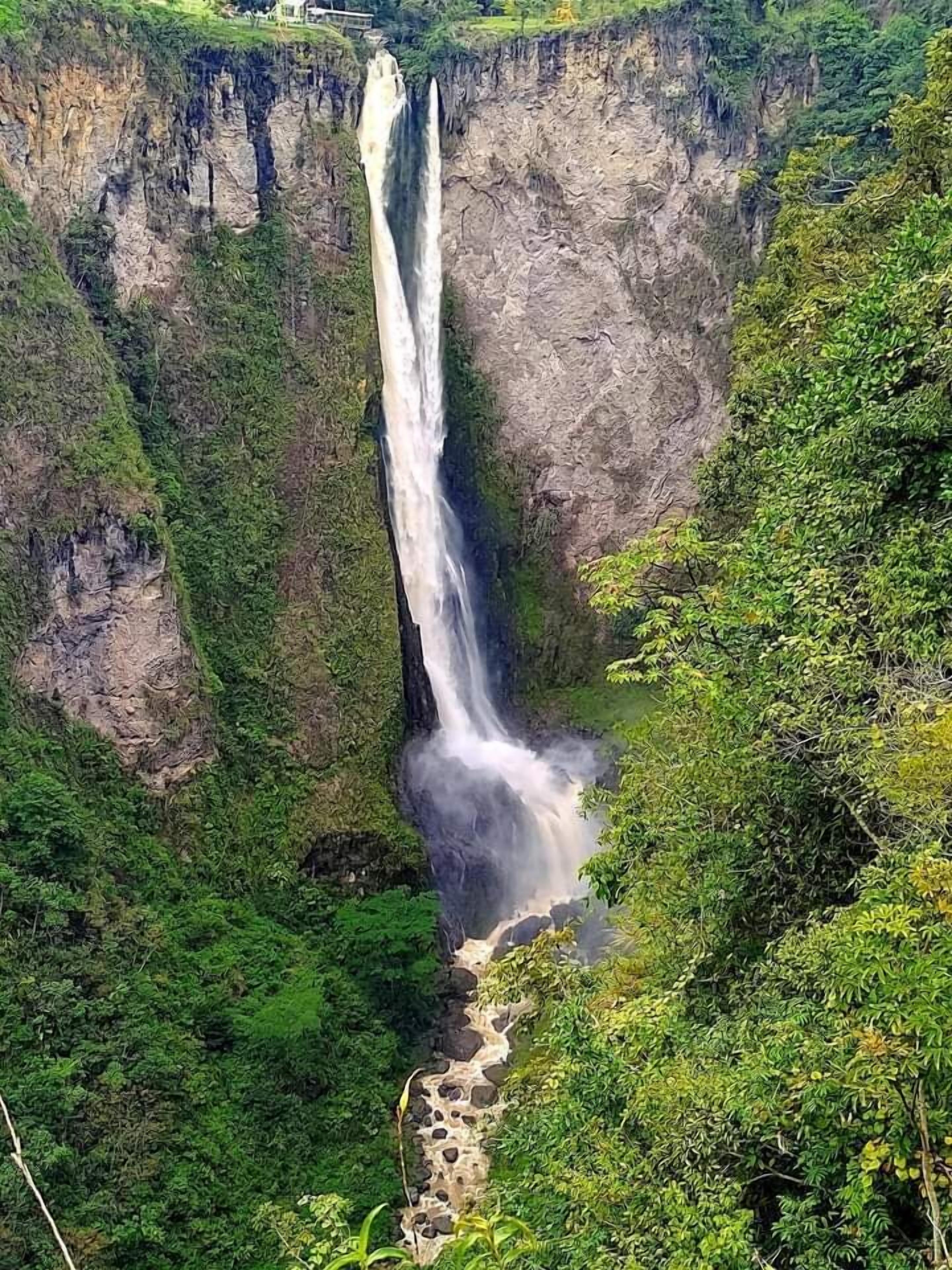 A waterfall cascading down a steep cliff surrounded by lush greenery.